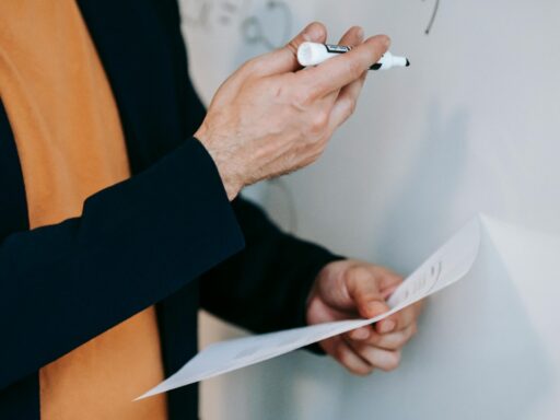 Teacher explaining something on board with holding paper in his hand