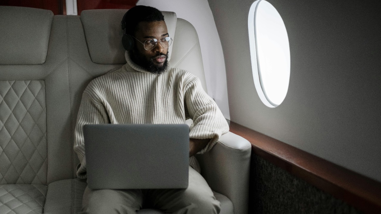 a man wearing headphones using a laptop in a luxrious aeroplane cabin
