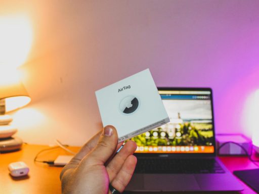 Hand holding airtag box in front of laptop